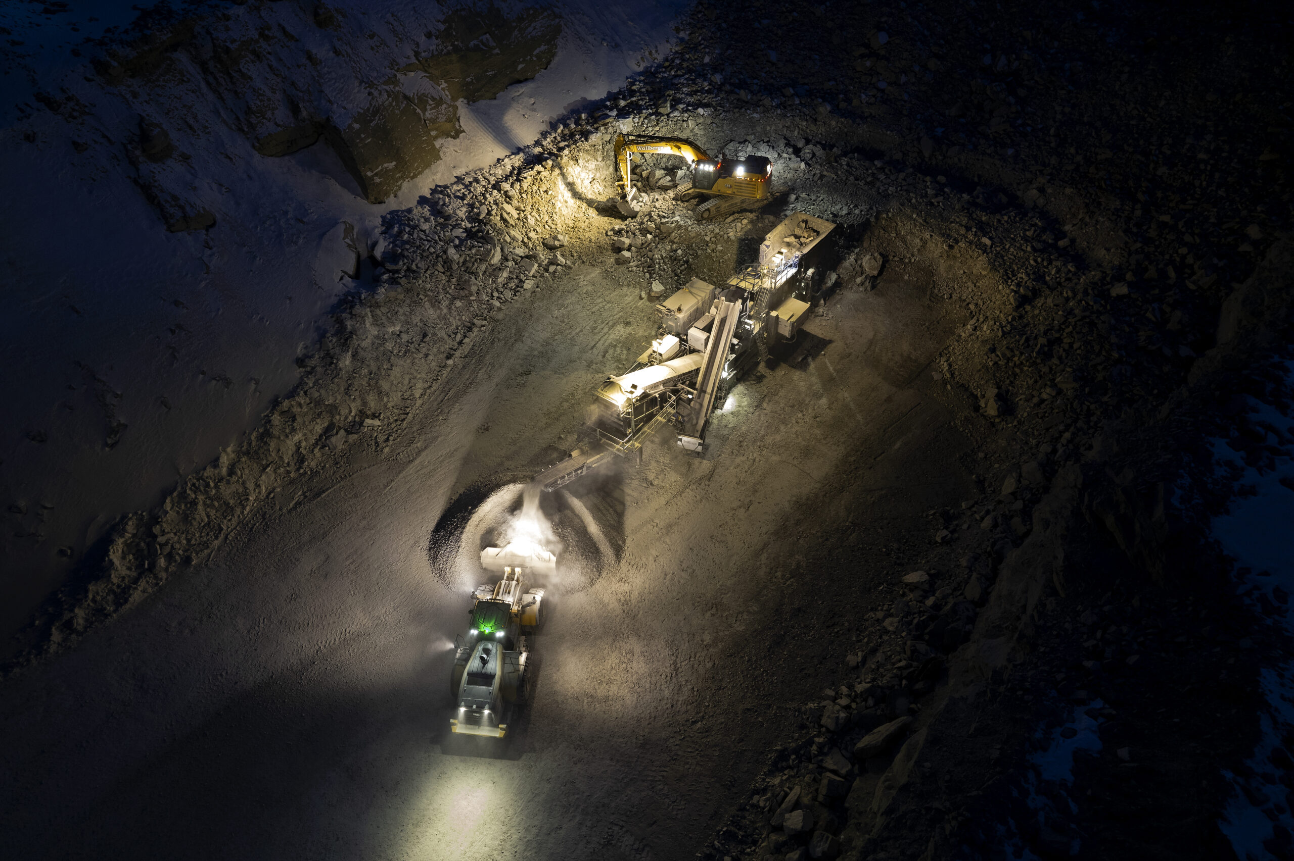 2 Wheeled Loaders work on a construction site in the dark. The machines are lit with the TYRI INTELLilight system and viewed from above.