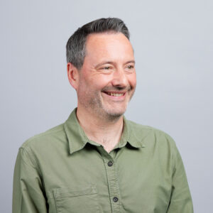 Head of Sales, Craig Gibbons wears a green shirt and looks off to the right of the camera.
